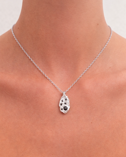 Necklace with a pendant on a person's neck against a neutral background
